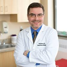 A smiling male doctor in a white coat.