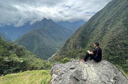 Basil Considine sitting on a rock looking into a mountain range