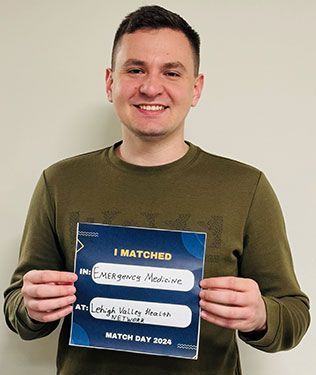 A man smiling holding a sign that says "I Matched in Emergency Medicine at Leigh Valley Health Network."