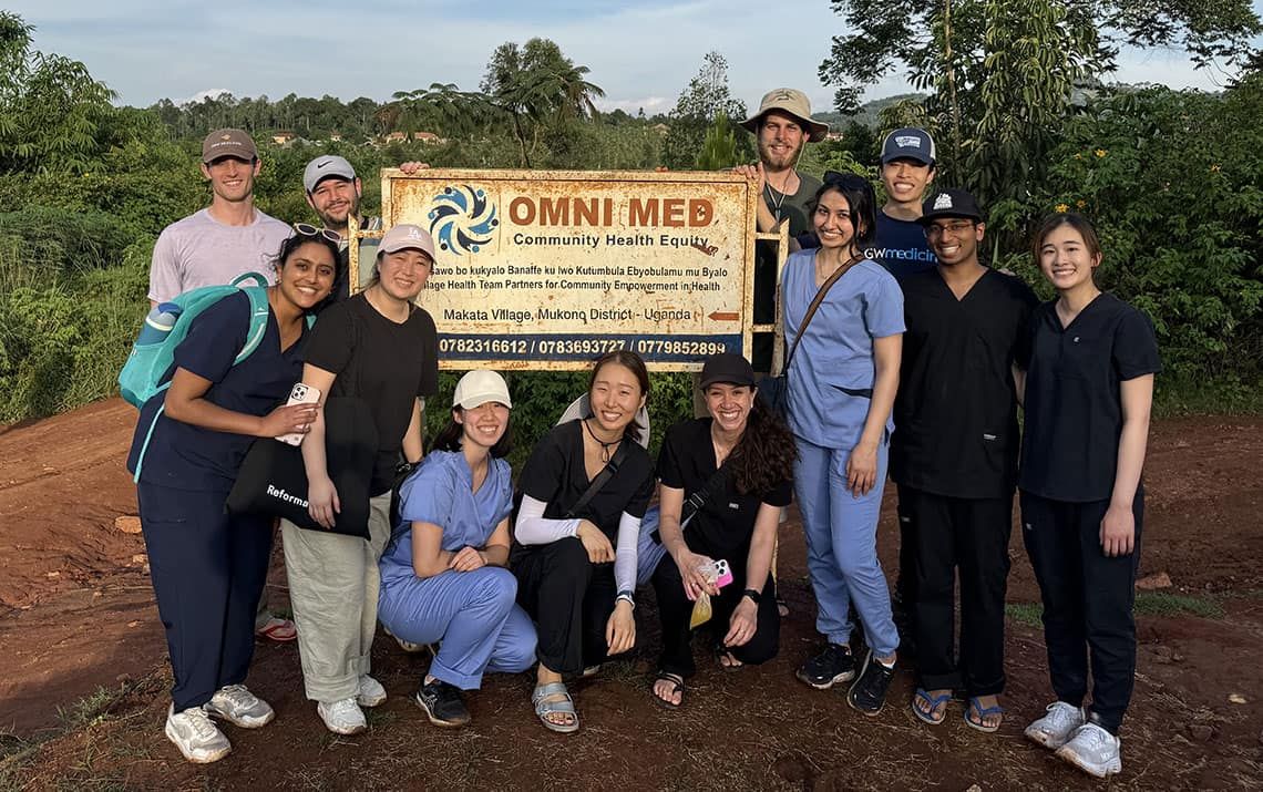 GW medical students posing in front of an Omni Med sign in Makata Village, Uganda